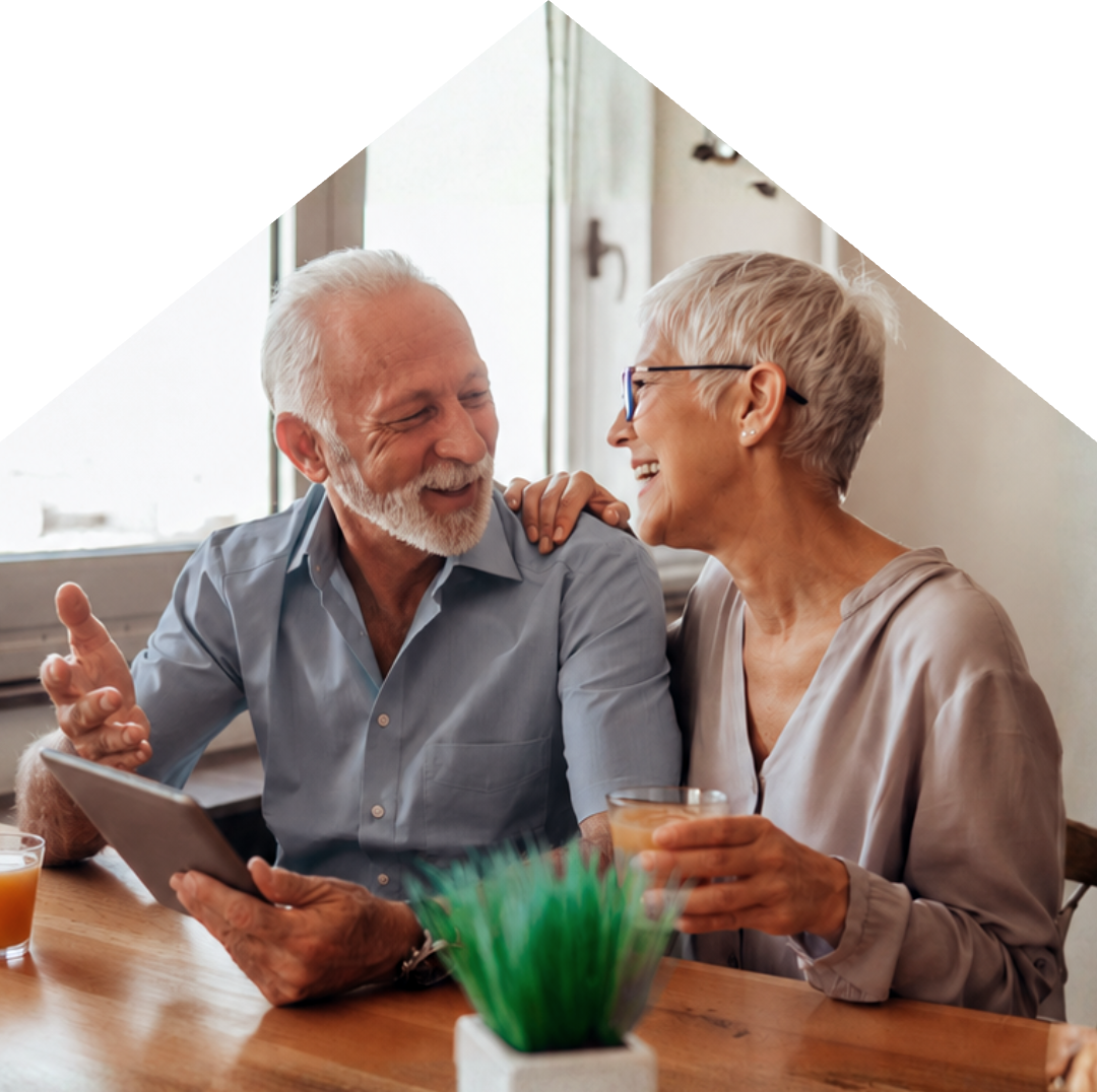 Retired couple laughing together over a tablet